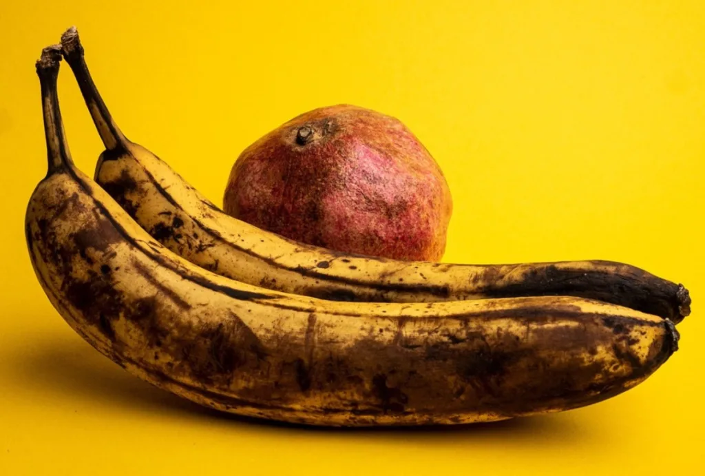 Banano y naranja en avanzado estado de deterioro, evidenciando residuos orgánicos que representan un problema ambiental y sanitario en los mercados públicos.