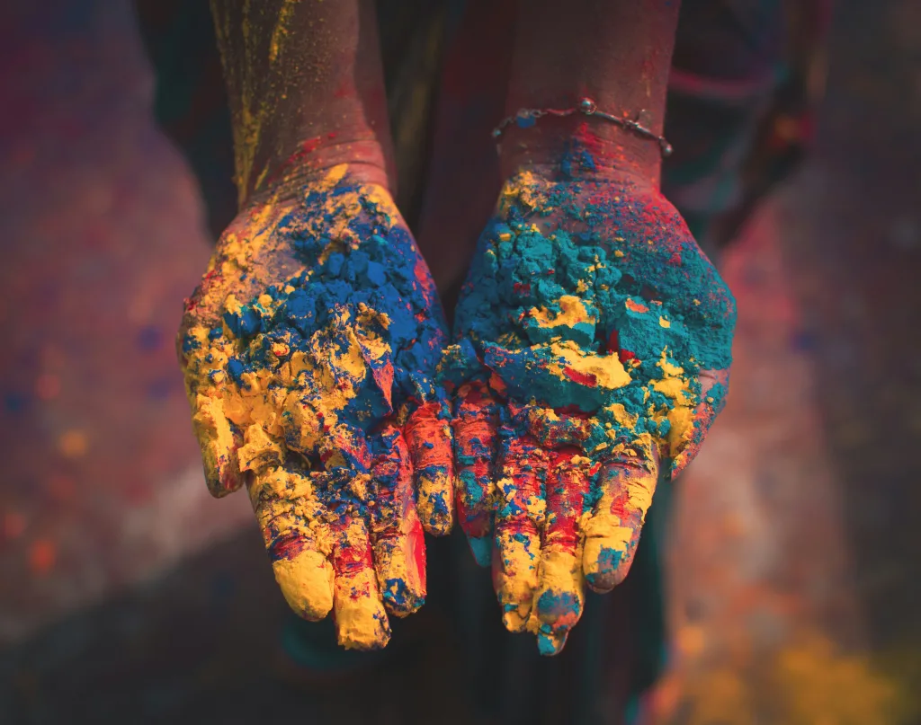 Manos sosteniendo polvos de colores durante la celebración del festival Holi. Foto de Debashis RC Biswas en Unsplash.