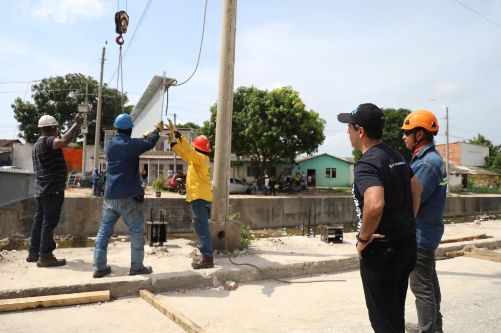 Trabajadores instalando estructura metálica sobre canal para la construcción de un parque lineal en el Malecón de Rebolo