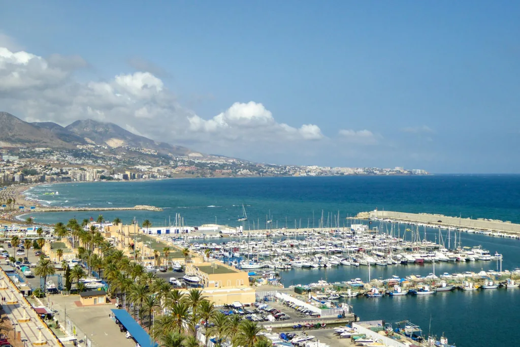 Vista aérea de una ciudad costera con puerto, playa y edificios junto al mar Mediterráneo.