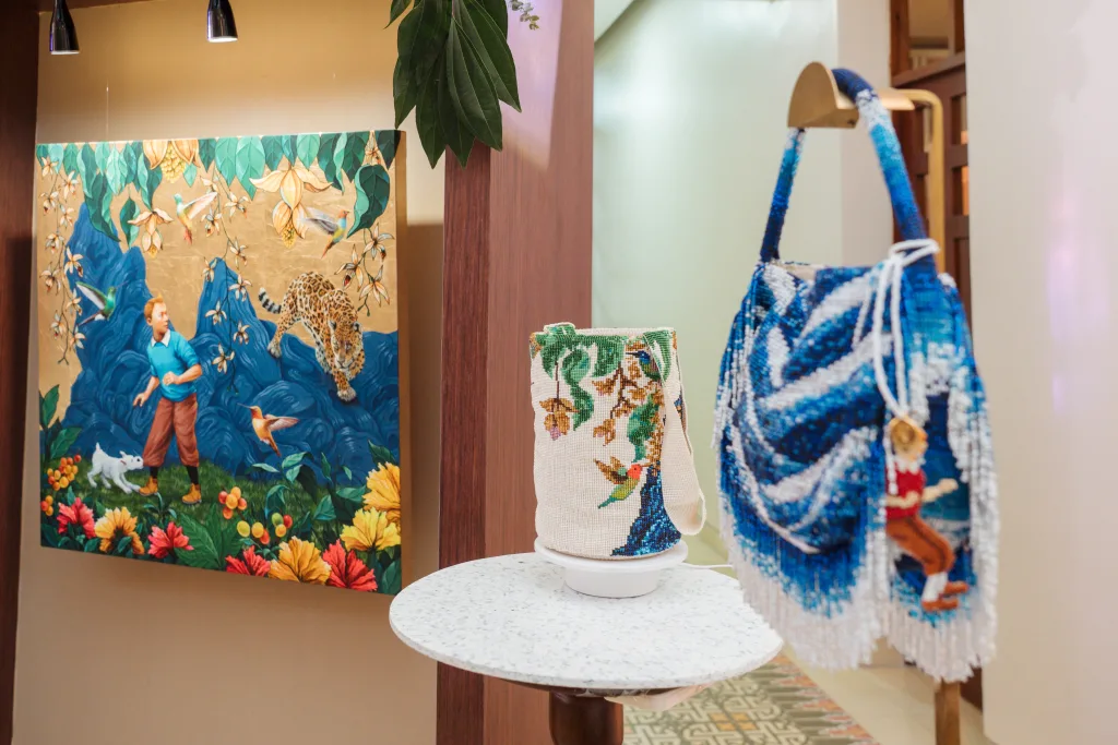 Obra de Gabriel Ortega que reinterpreta a Tintín en un entorno caribeño, acompañada de bolsos intervenidos con diseños inspirados en la pieza.
