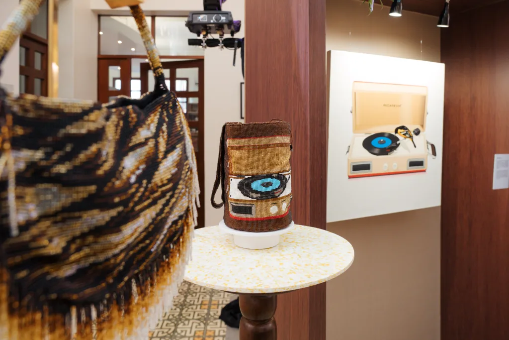 Bolsos intervenidos con técnicas artesanales exhibidos junto a una obra artística durante la quinta versión de Lazos y Trazos.