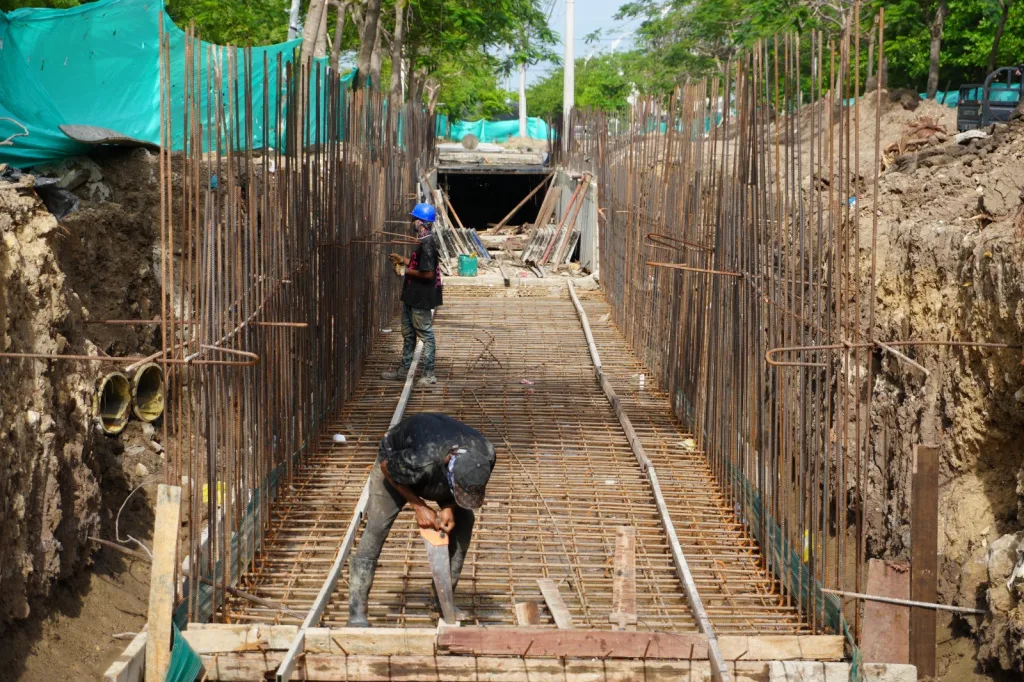 Trabajadores construyendo la losa sobre el canal en las obras del parque lineal de Caribe Verde