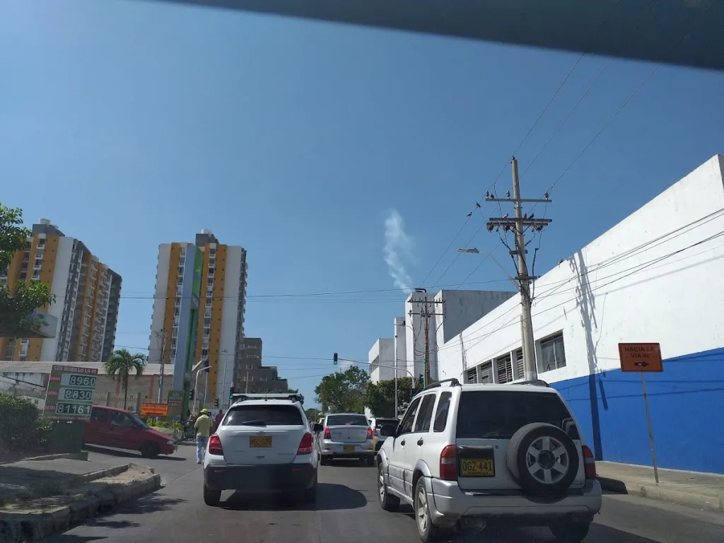 Tráfico en una avenida urbana bajo sol fuerte, con edificios, palmeras y señales viales, ilustrando el impacto del calor extremo en la movilidad y la vida diaria.