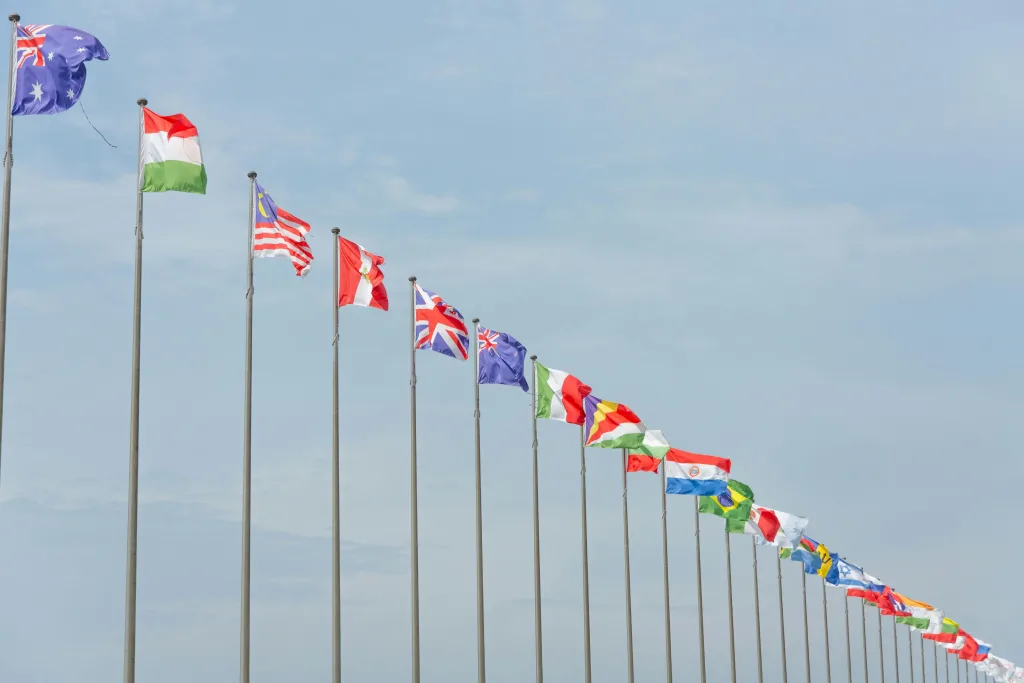 Fila de banderas de distintos países ondeando en un cielo azul.