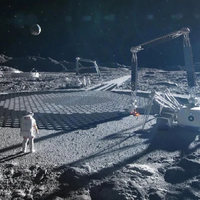 Robots y un astronauta trabajando en la construcción de una plataforma en la superficie lunar.