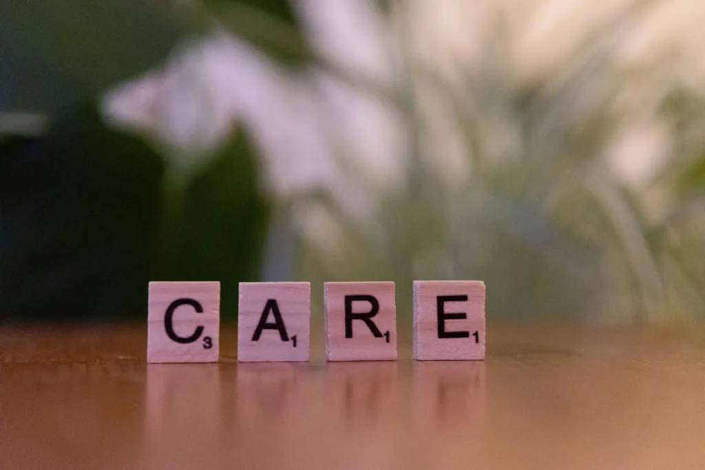 Fichas de madera formando la palabra CARE, simbolizando cuidado, apoyo y atención