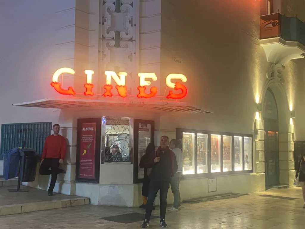 Fachada iluminada del Cine Albéniz de Málaga con personas entrando por la noche