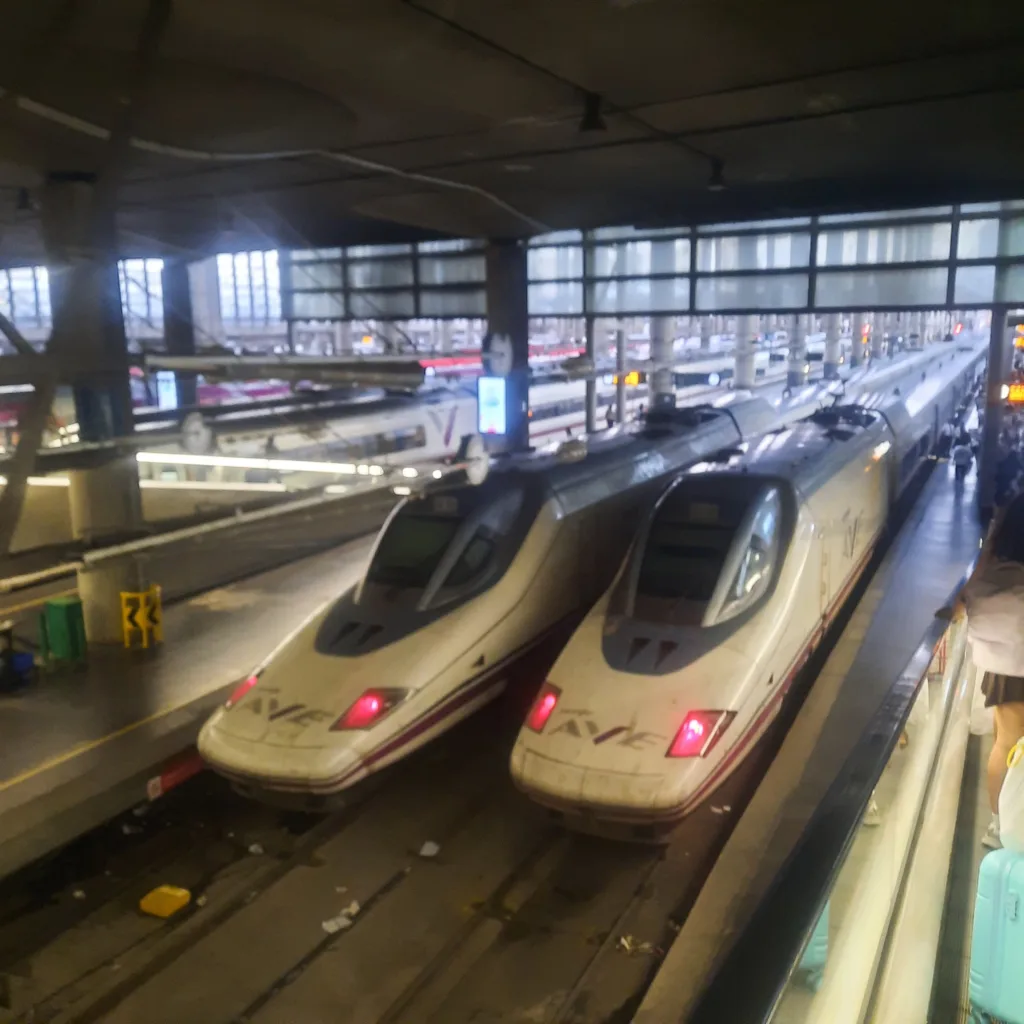 Trenes AVE estacionados en Atocha, Madrid, infraestructura ferroviaria moderna y sostenible.