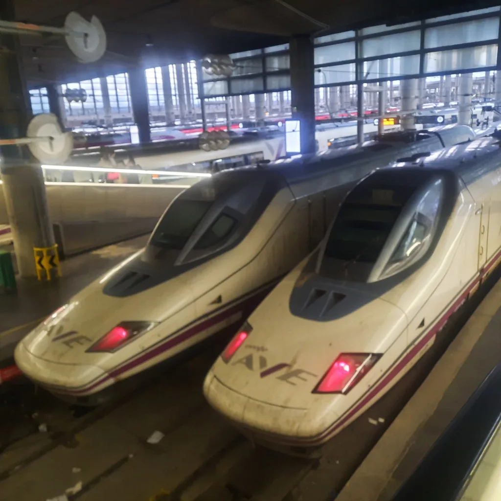Dos trenes AVE detenidos en una estación española, infraestructura moderna del sistema ferroviario de alta velocidad.